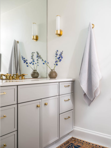 Custom bathroom cabinetry with gold hardware and matching light fixtures