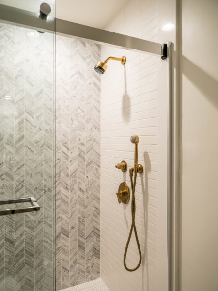 Grey tiled walk in shower with gold faucet