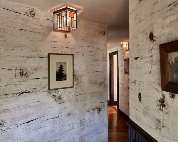 Birch bark inspired walls with stained glass sconce and hardwood floors