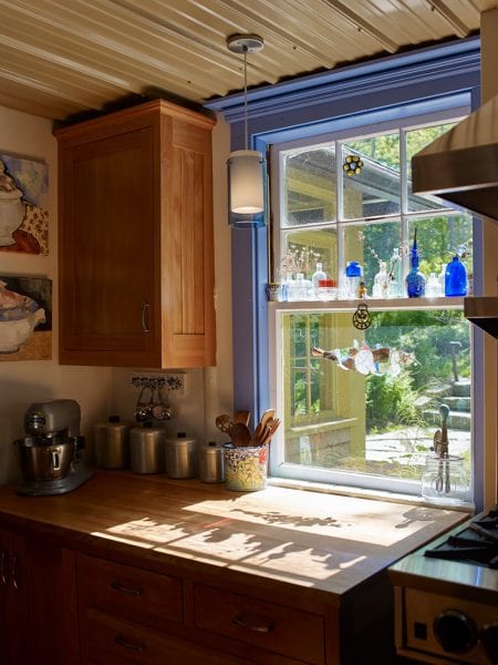 The kitchen features vibrant trim around the windows, tin ceiling, and wide counterspace.