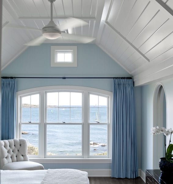 Bright and calming bedroom with modern ceiling fan and coastal views