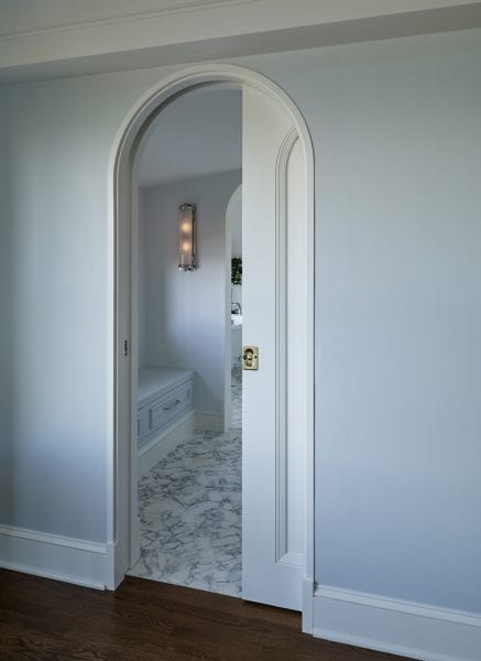 A rounded doorway with pocket doors leading to the relaxing bathroom.