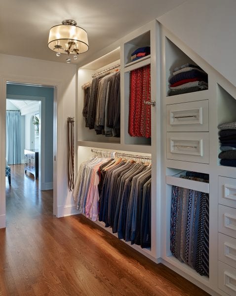 Walk-in closet with hangning racks, tie racks, and drawers for storage.