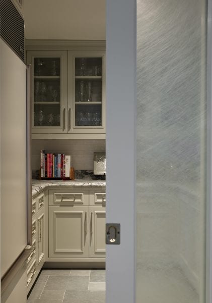 A look at the pantry with set-in freezer, counter space, storage, and frosted pocket door.
