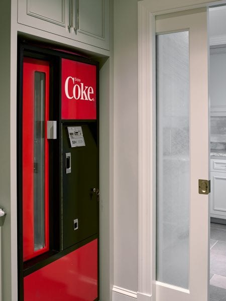 A vintage Coke soda vending machine near the frosted pocket door to the kitchen.