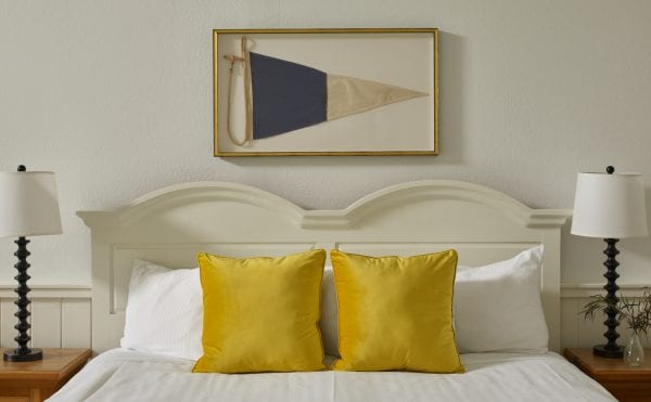 Reclaimed flag above bed with vibrant yellow pillows