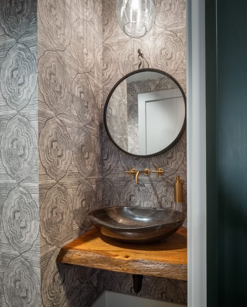 Dynamic wallpaper, stone bowl sink and live edge vanity in this office restroom