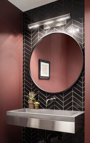 Dramatic tile backsplash and stone sink in office bathroom