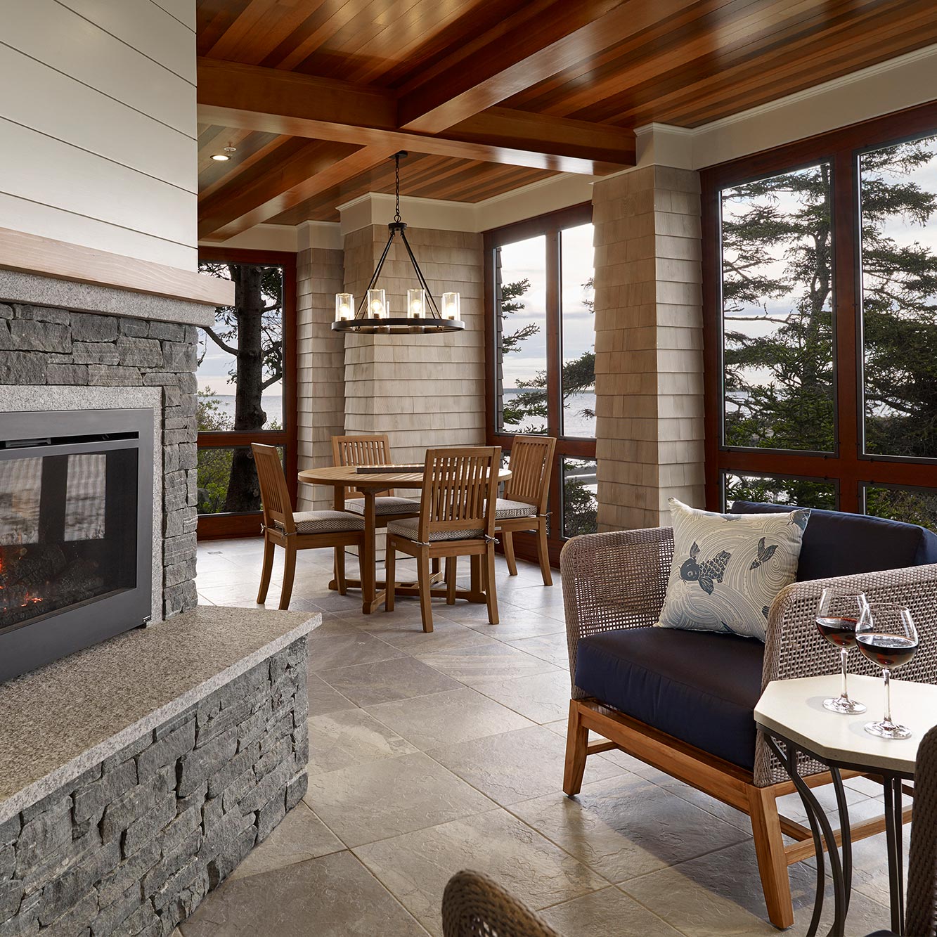 Outdoor fireplace with rustic chandelier, tile and polished wood details, and coastal views.