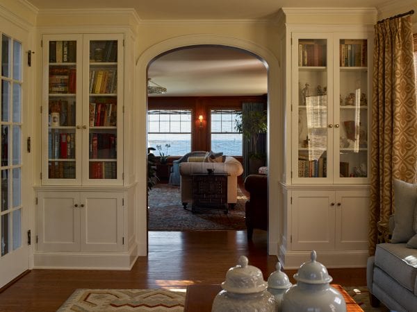A cozy library or den space with coastal views, and built-in bookselves with glass doors.