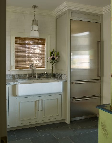 A view of the large farm sink, set-in refrigerator, and marbled countertops.