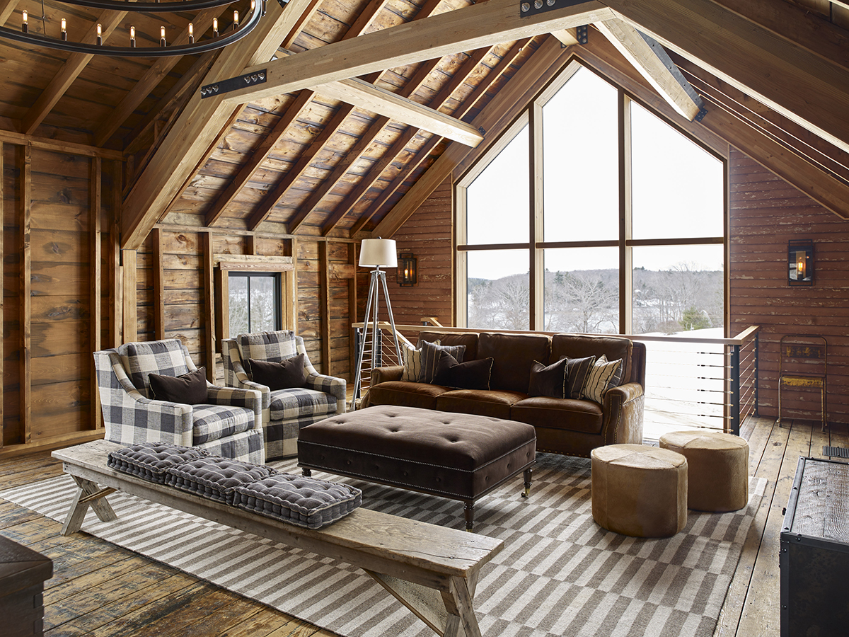 Cozy, rustic, and spacious living room with large picture windows and exposed beam.