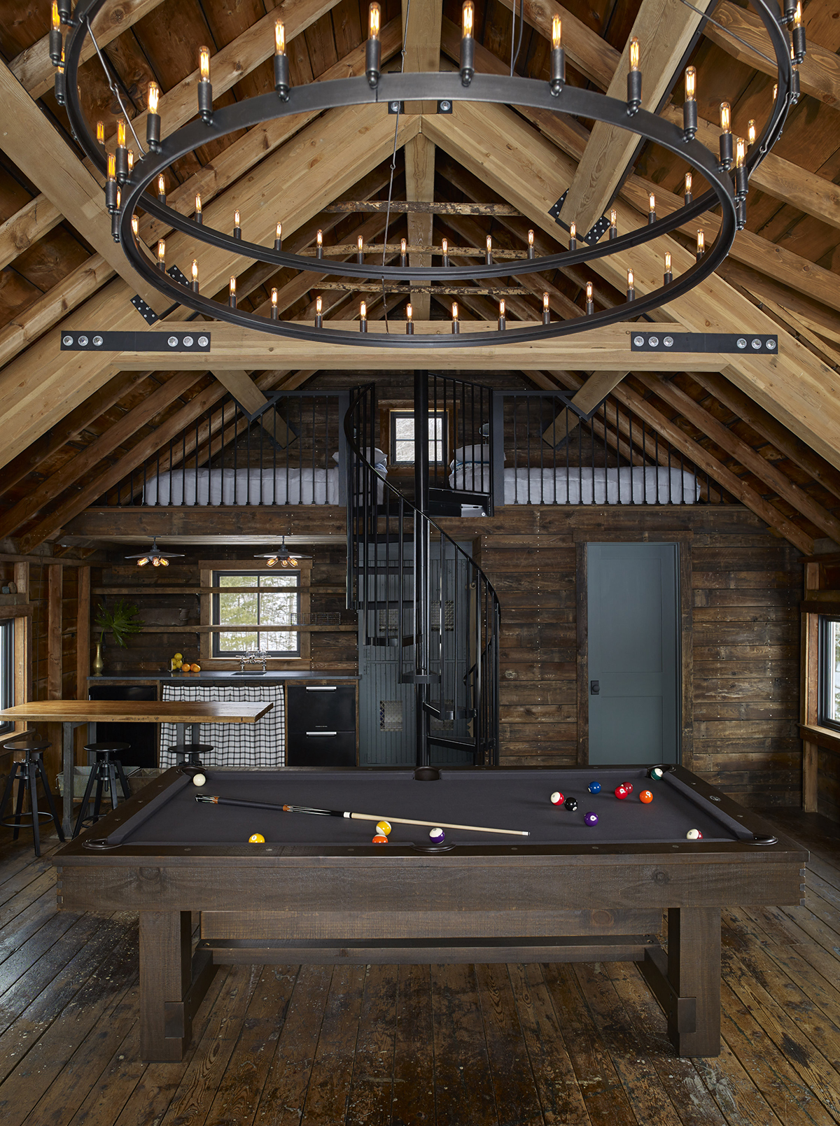 The pool table under the rustic chandelier and cathedral ceilings