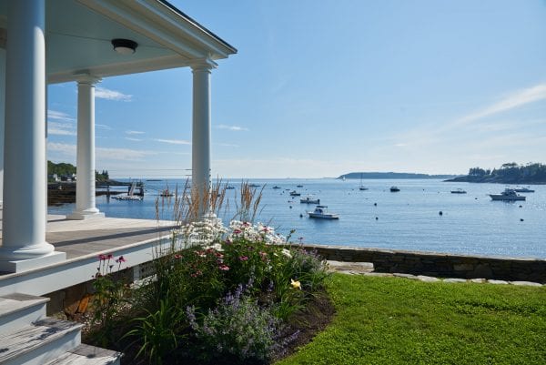 Coastal views from Twin Cove property with stone wall details and flower gardens along the wrap porch.