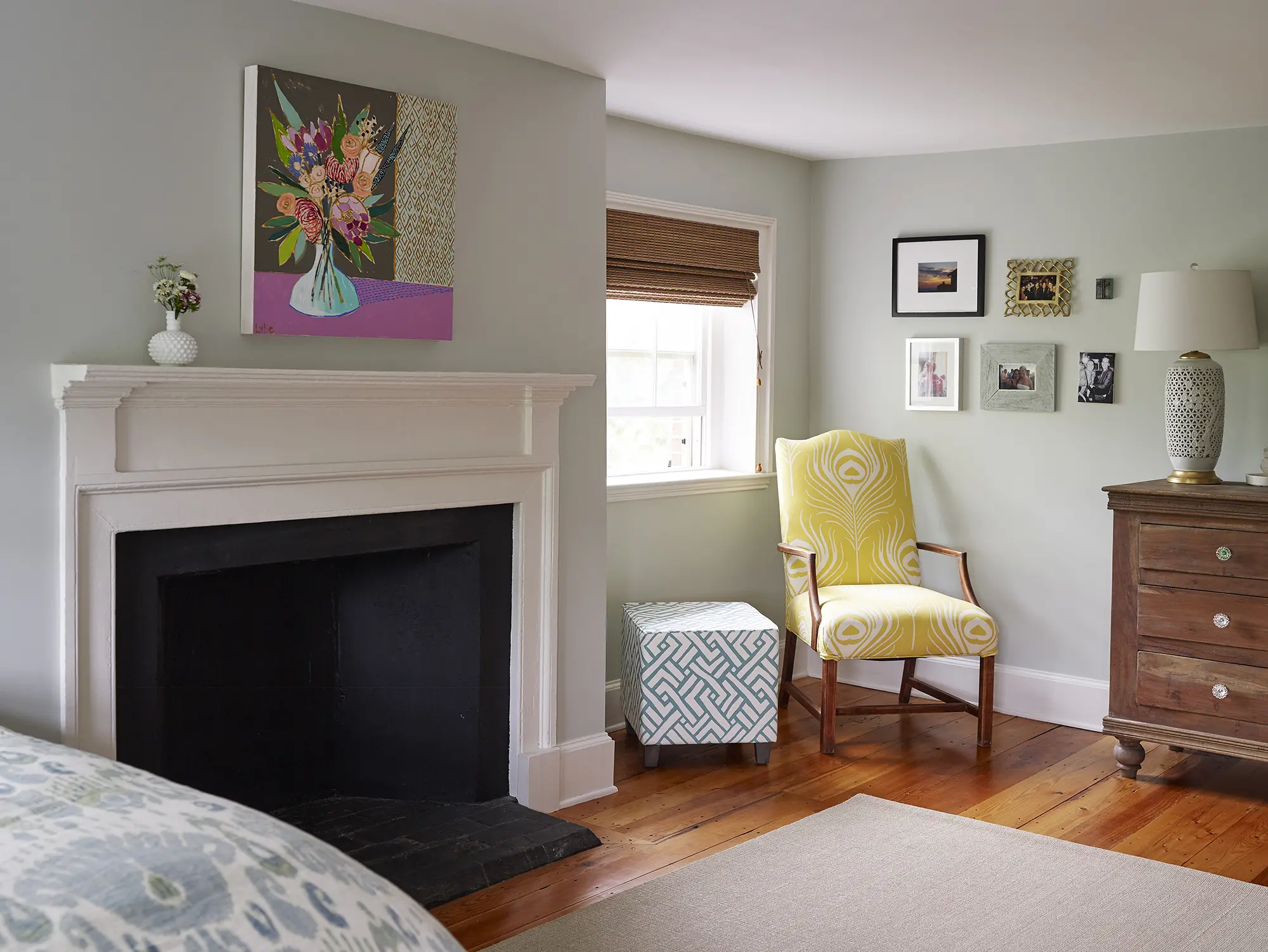 Fireplace in primary bedroom chair upholstered in peacock feather fabric